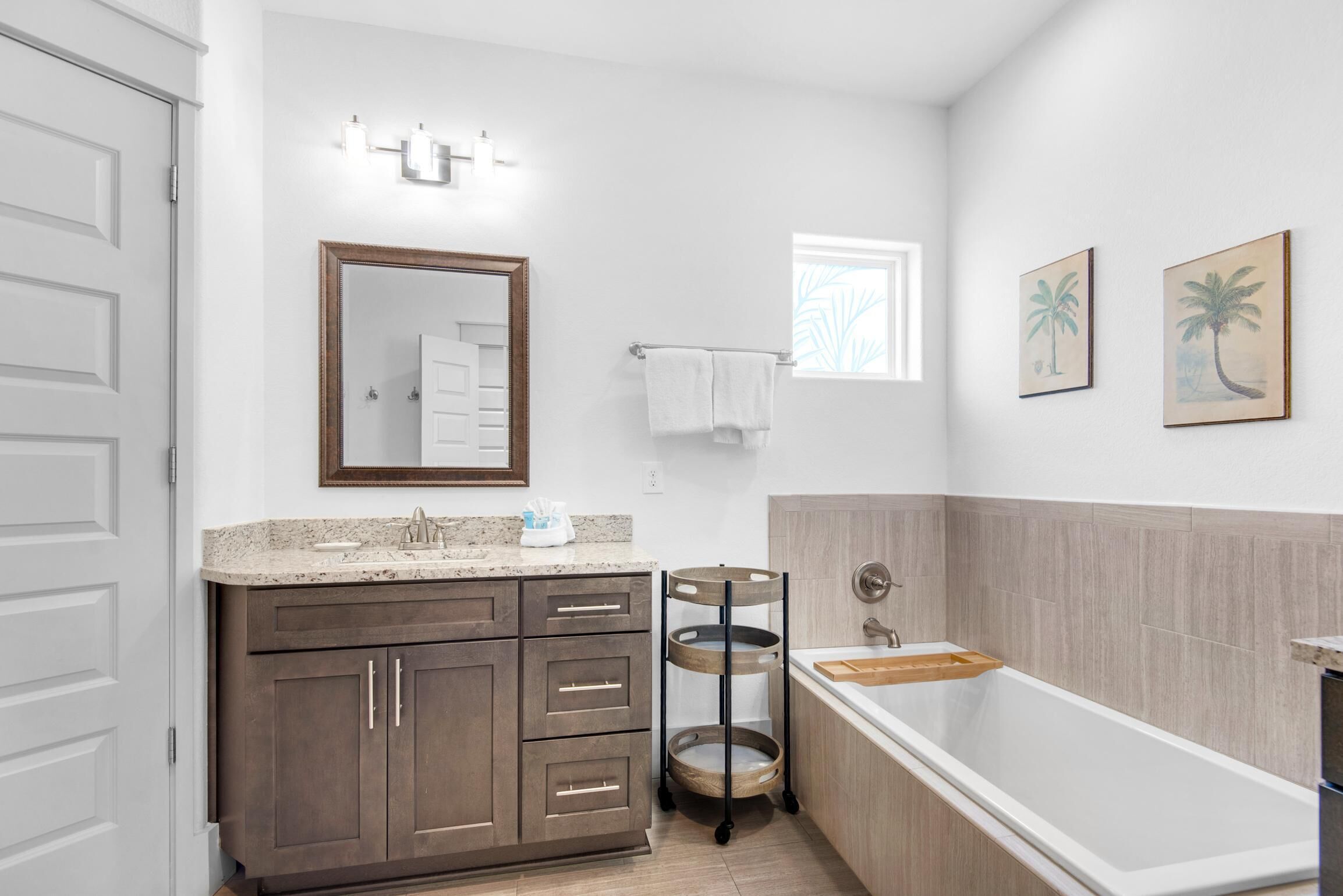 A modern bathroom with a freestanding bathtub, a vanity with a granite countertop, and a mirror above the sink.