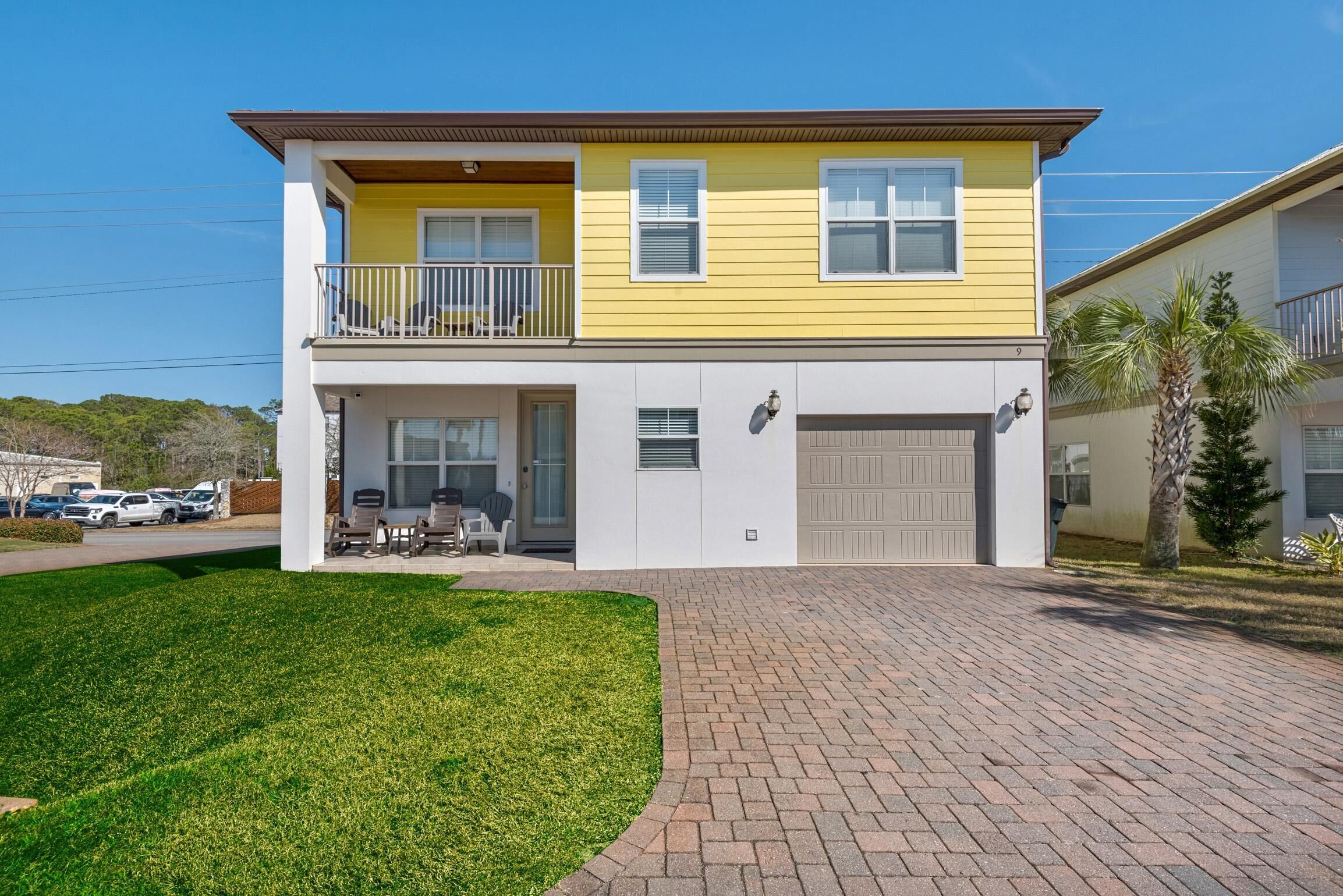 Une maison à deux étages avec une façade jaune, un balcon et un garage.
