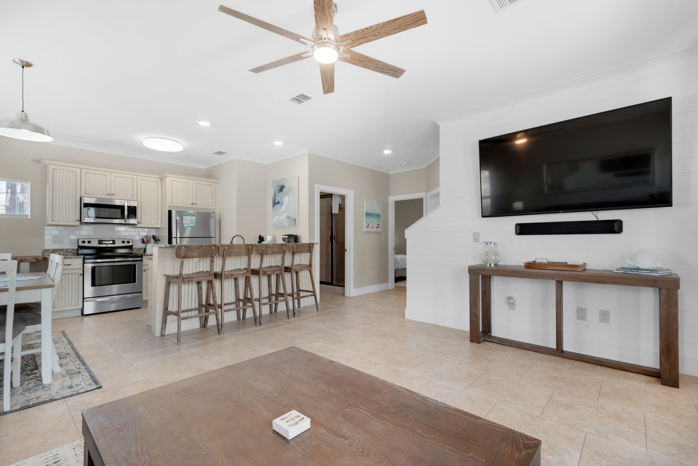A modern kitchen with white cabinets, stainless steel appliances, and a dining area with wooden chairs.