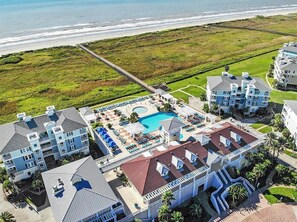 A resort with a large pool, multiple buildings, and a pier extending to the beach. - Directly on the beautiful Gulf Coast in Pointe West, Galveston, TX (Galveston)