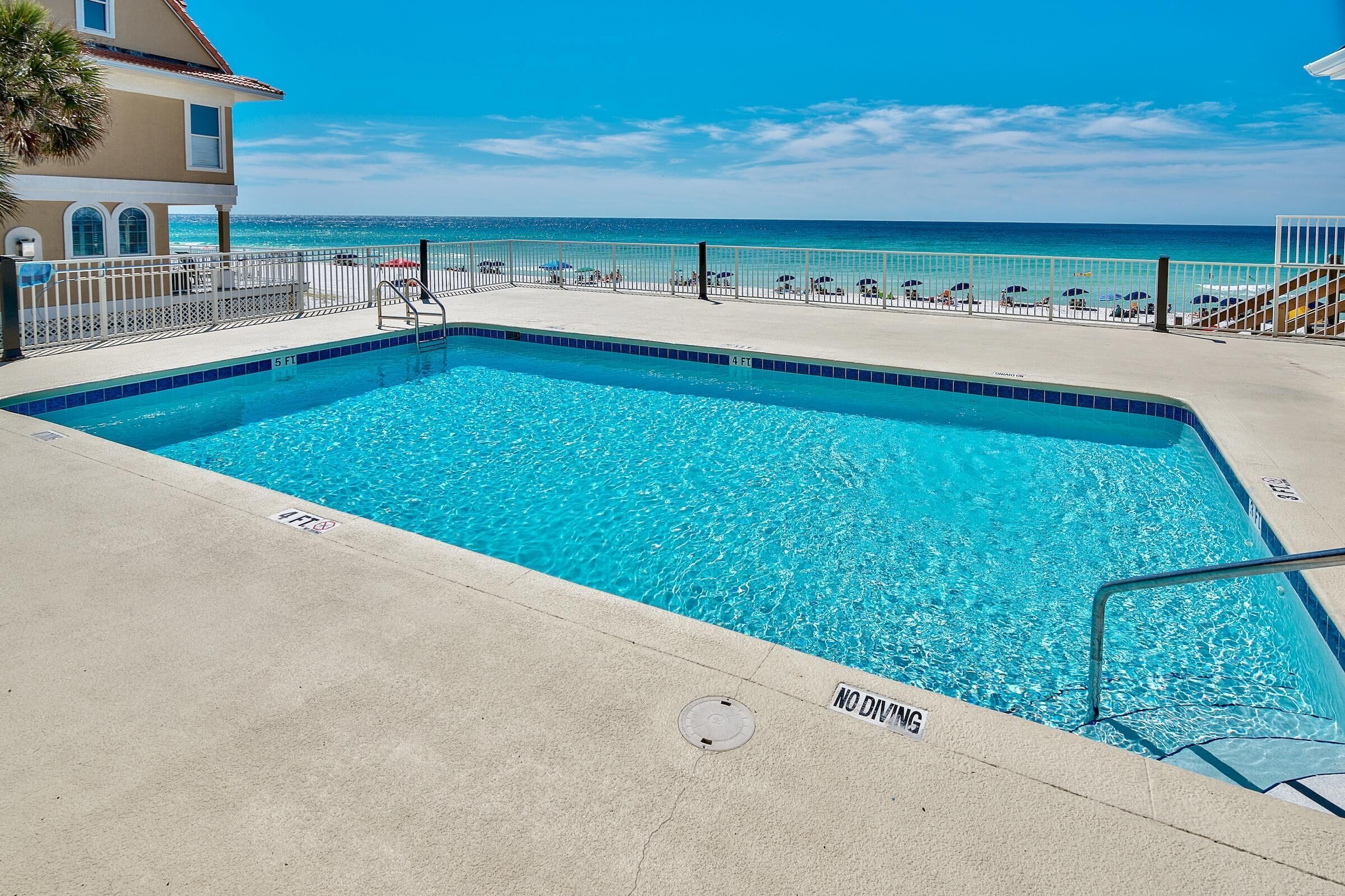 A swimming pool with a view of the ocean, a no diving sign, and a lifeguard chair.