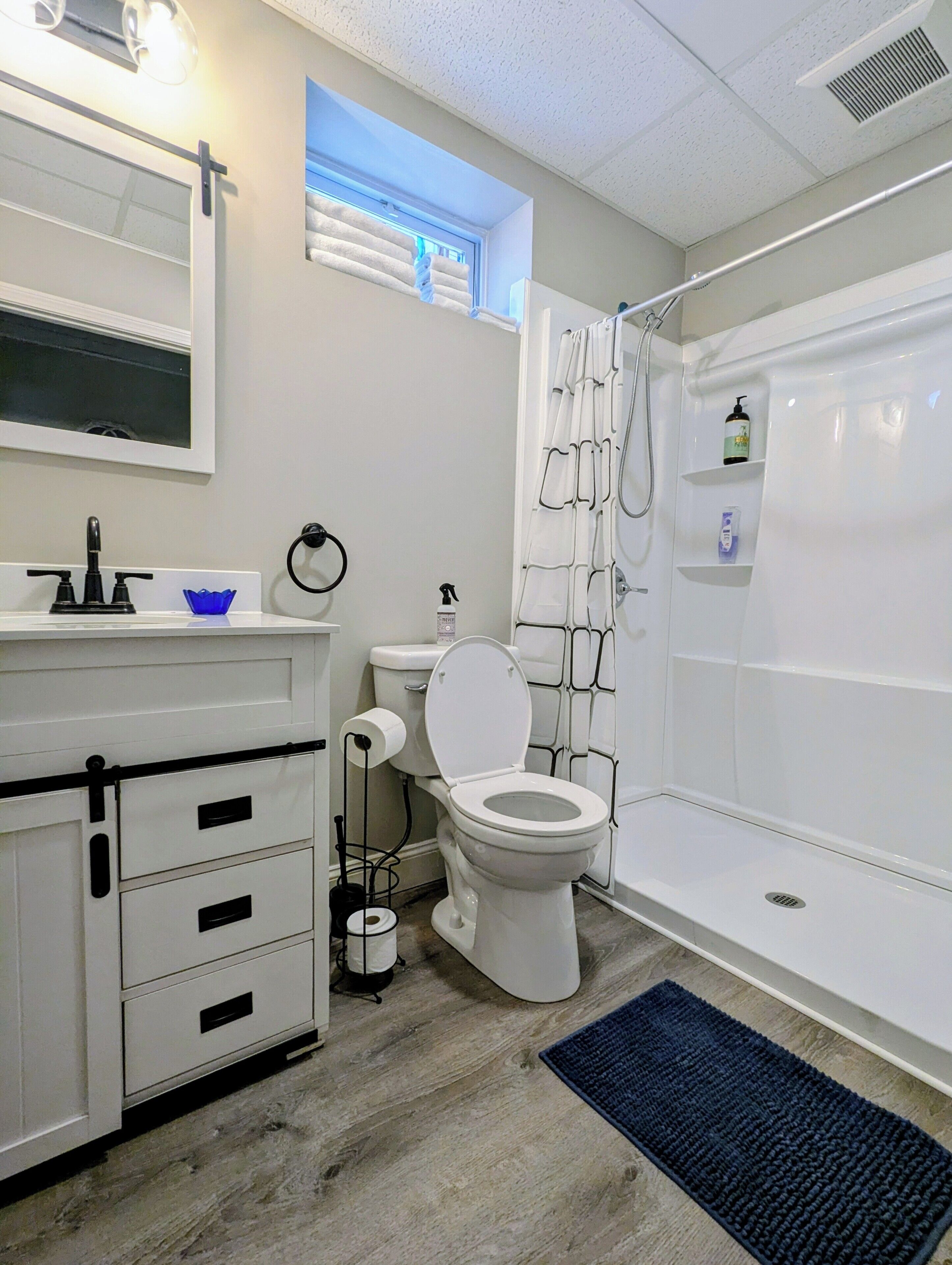 Un baño con inodoro, lavabo, espejo y ducha.