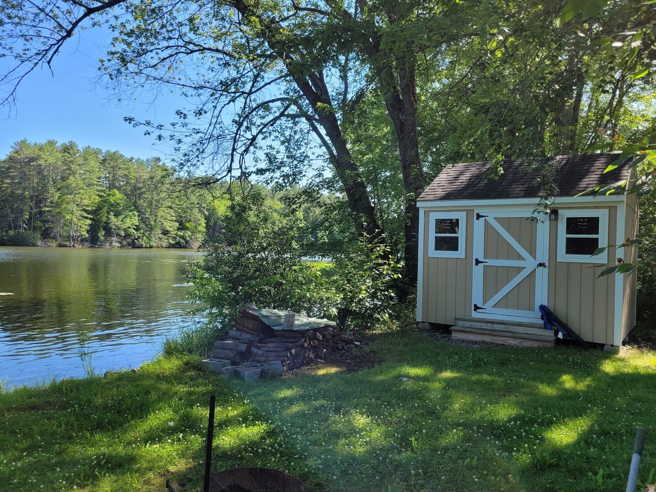 A small shed by a lake with a clear view of the water and surrounding trees.