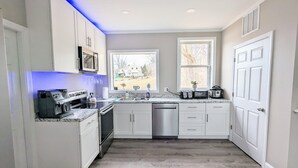 A modern kitchen with white cabinets, a stainless steel dishwasher, and a granite countertop. - Maine river escape: free kayaks, paddle boards, tennis, cute rabbits and fun! (West Gardiner)