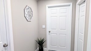 A hallway with a wooden floor, white walls, and a white door at the end. - Maine river escape: free kayaks, paddle boards, tennis, cute rabbits and fun! (West Gardiner)