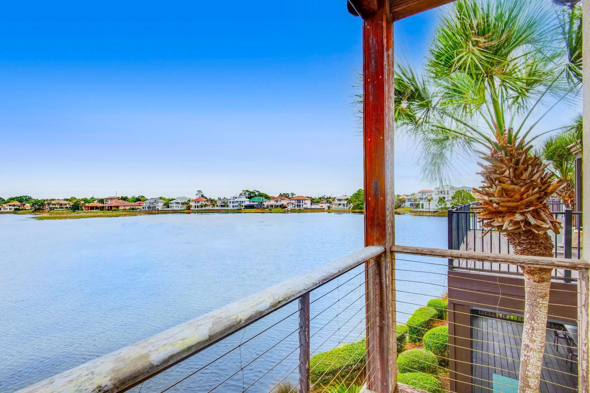 A waterfront property with a view of the water, a wooden deck, and a palm tree.