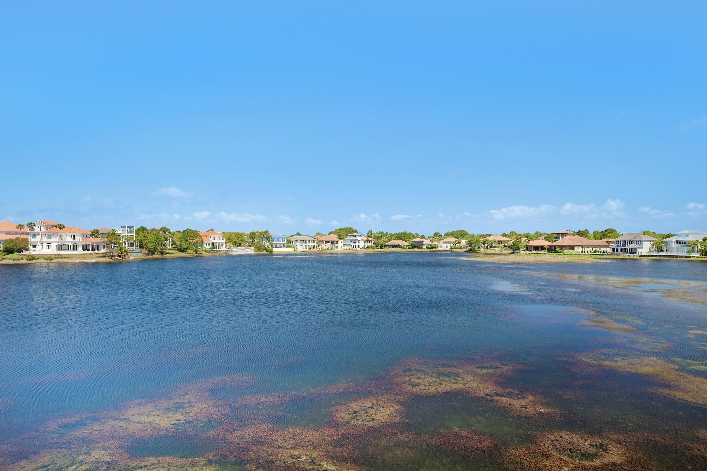 Zona residencial a orillas del lago, con casas a lo largo de la costa y un cielo azul despejado.