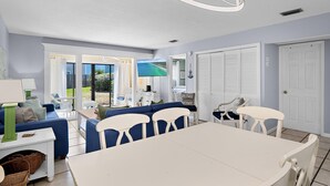 A room with a dining table, chairs, a sofa, and a television. - Chateau La Mer #5B (Destin)