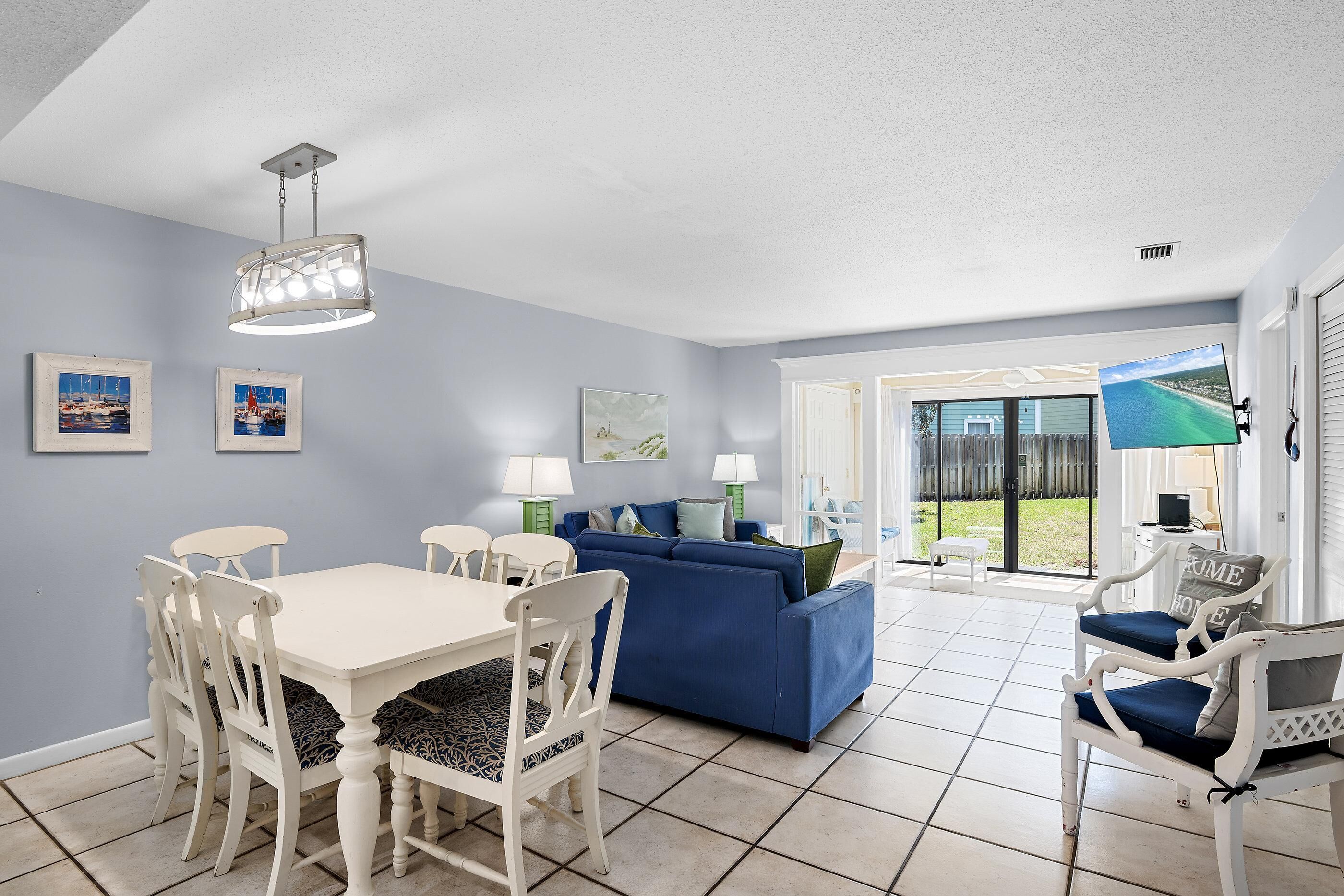 A living room with a dining table, chairs, a blue sofa, and a ceiling light fixture.