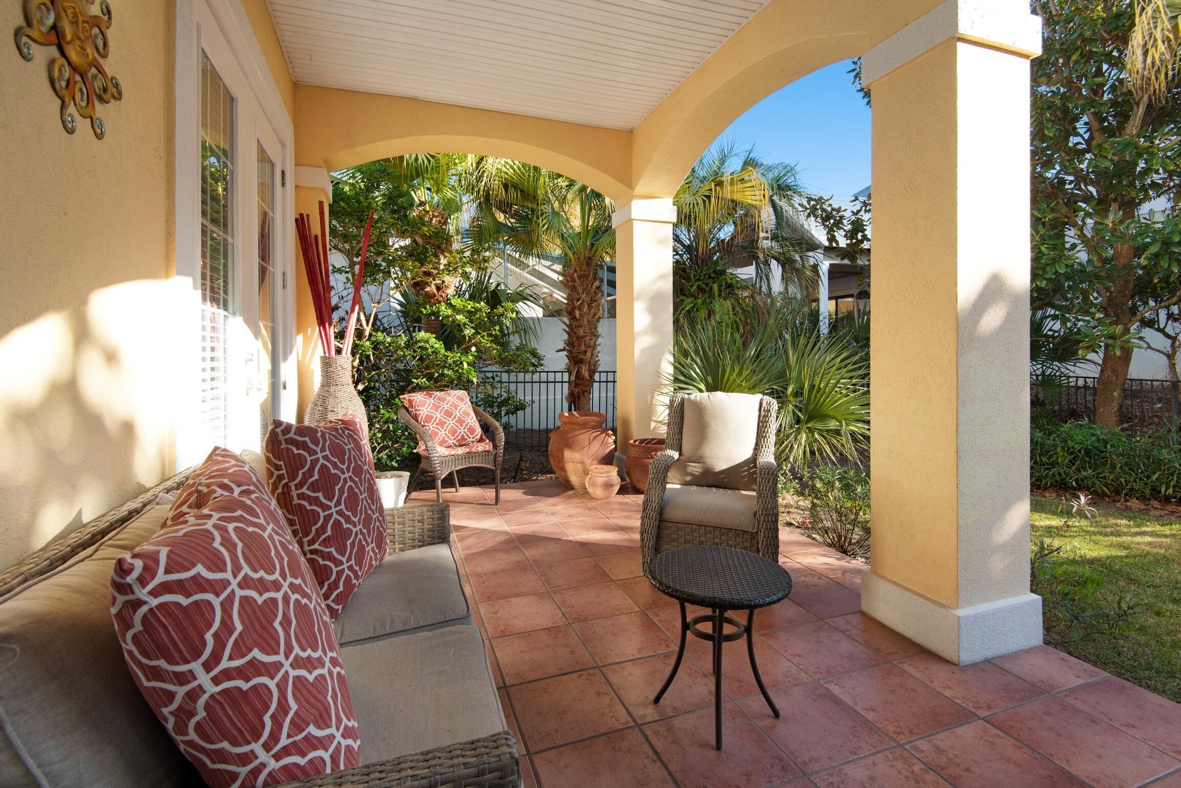 A covered patio area with wicker furniture, including a sofa and chairs, and a small round table.