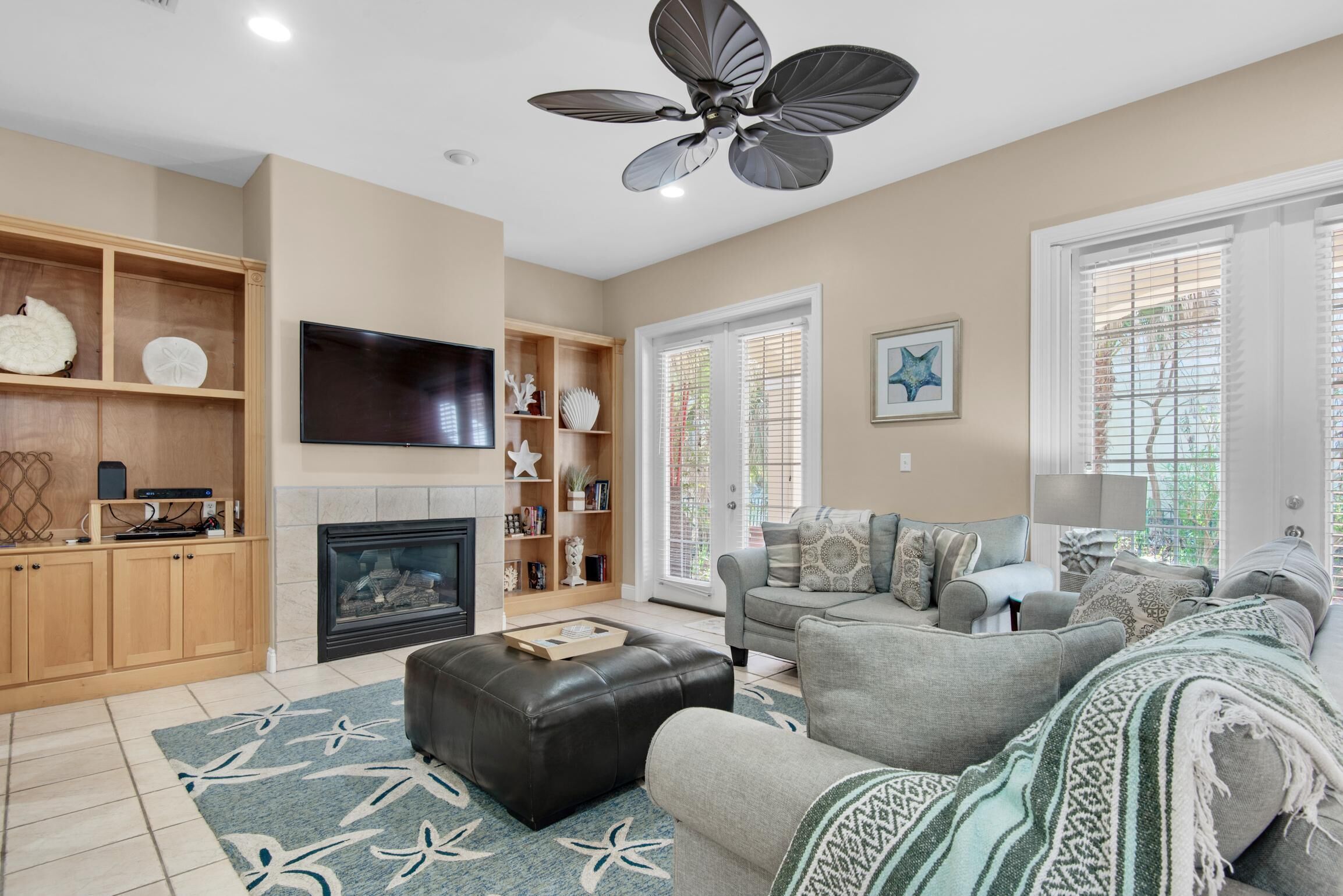 A living room with a fireplace, a ceiling fan, a television, and a sofa.