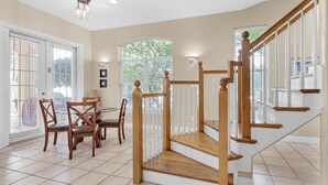 A dining area with a wooden staircase leading to an upper floor. - Bonaire Retreat (Destin)