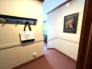 A hallway with a white wall, a framed picture of a historical figure, and a white bag hanging on the wall. - Village Hideaway - Telluride convenience! (Telluride)