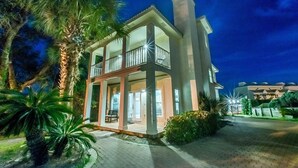 A two-story building with a balcony, surrounded by palm trees and a paved driveway. - Another Day in Paradise (Destin)
