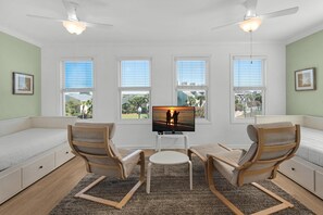 A room with a bed, two wooden chairs, a small table, and a TV on a white stand. - Another Day in Paradise (Destin)