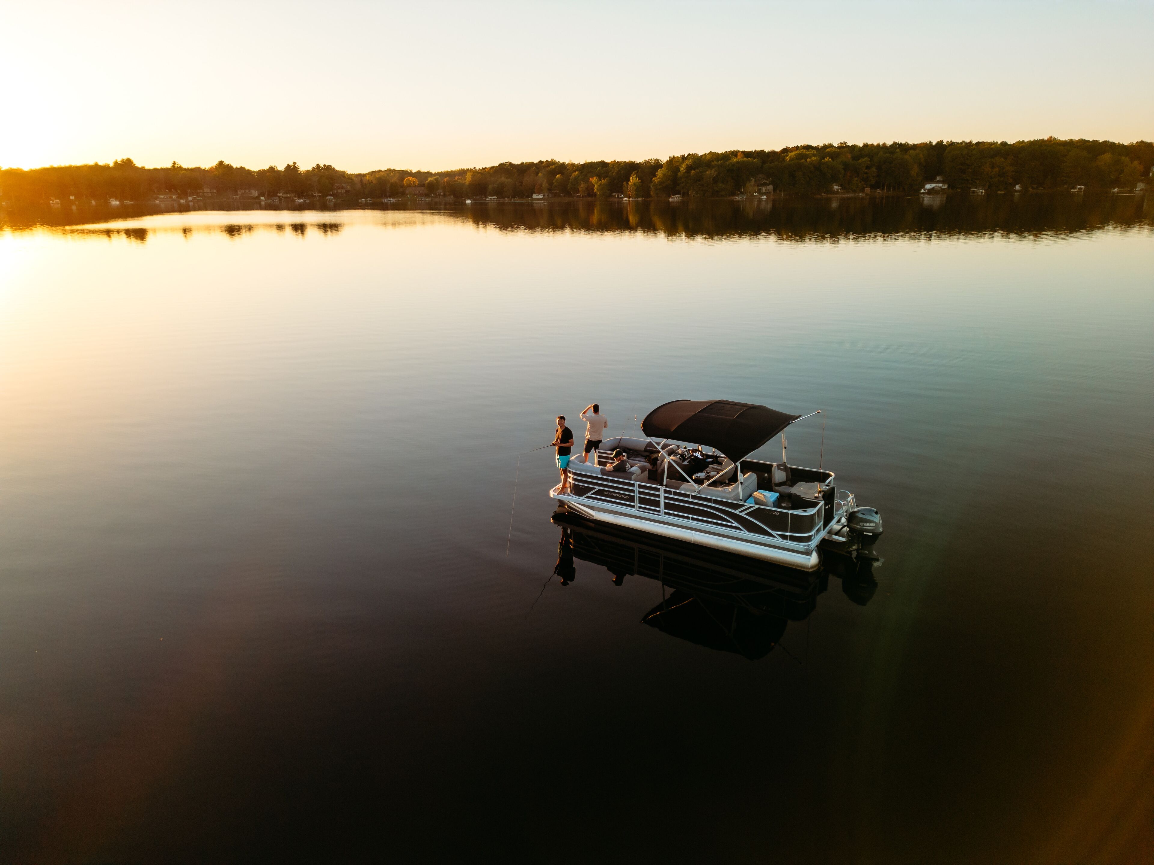 Un bateau est amarré sur un lac paisible, avec une rive boisée en arrière-plan.