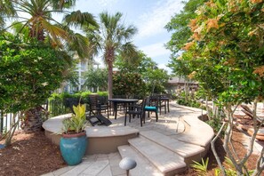 An outdoor patio area with stone steps, a round table, and chairs. - Serenity (Destin)