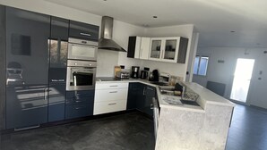 A modern kitchen with dark cabinetry, a built-in oven, and a large island with a sink.