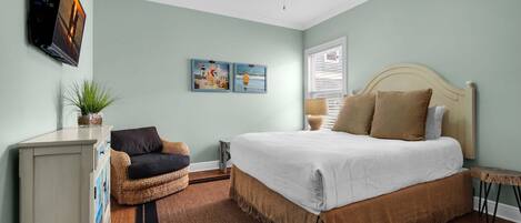 A bedroom with a bed, a dresser, a chair, a ceiling fan, and wall art.