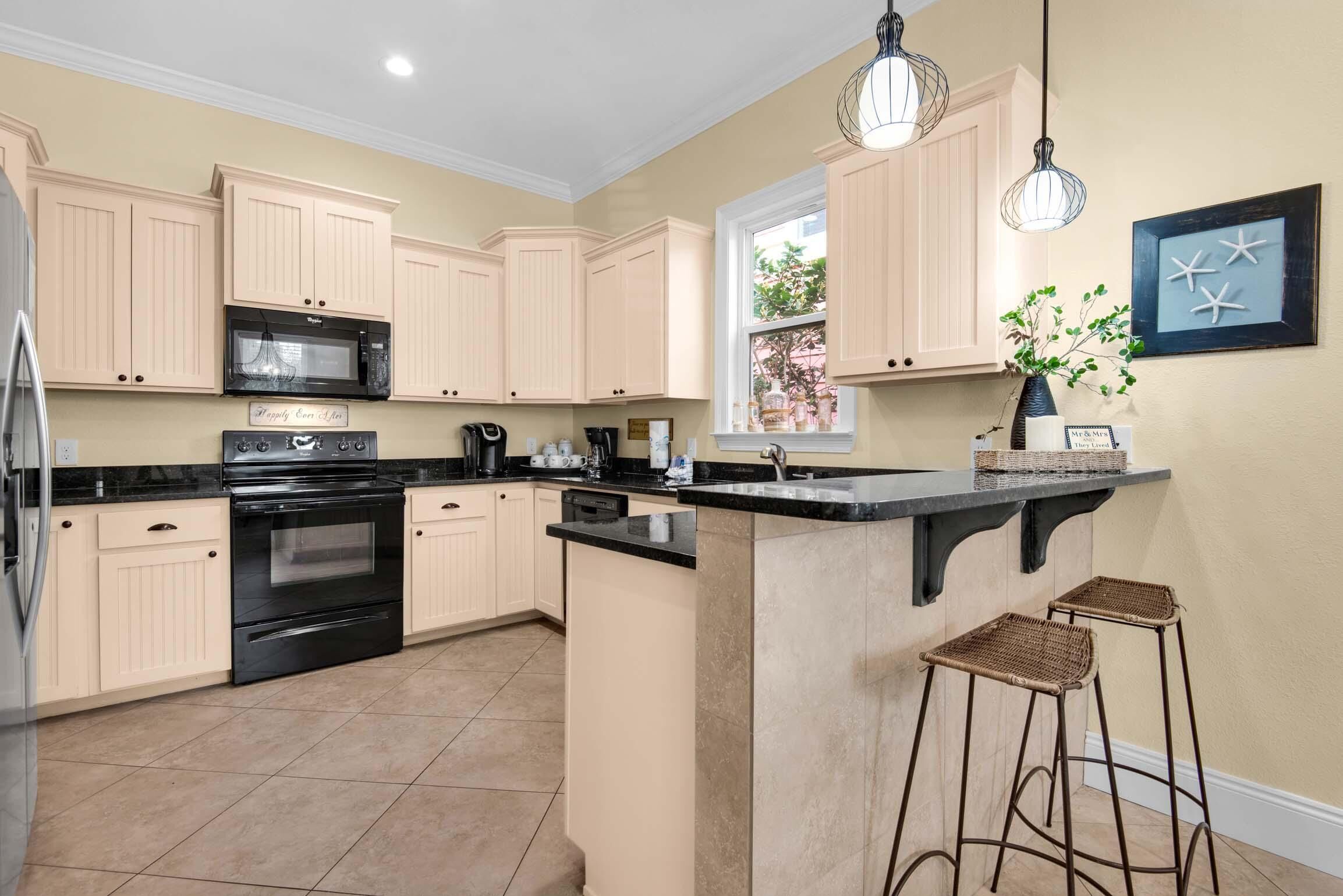A kitchen with light-colored cabinets, a black stove, and a central island with stools.