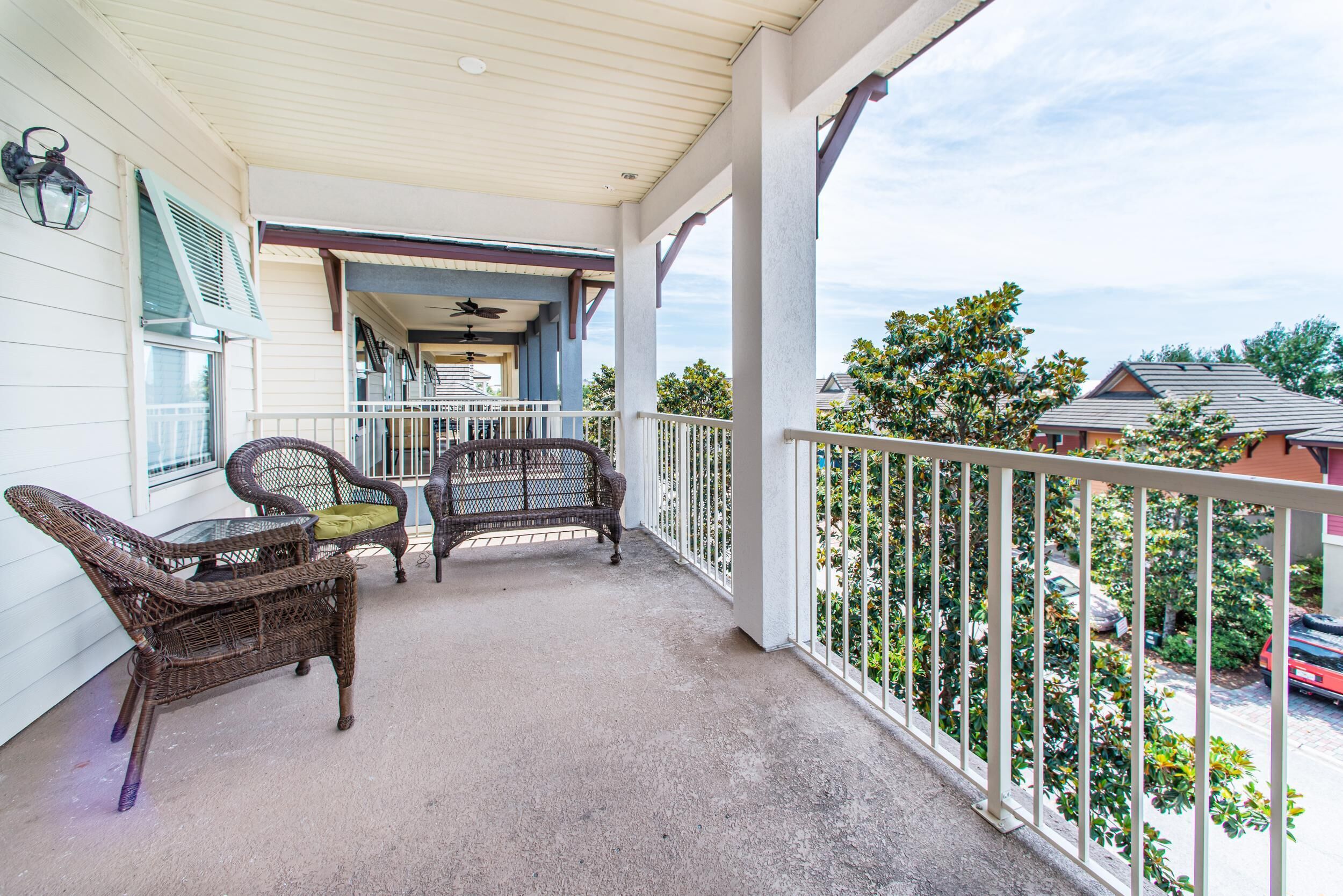 A covered porch with wicker furniture and a view of the neighborhood.