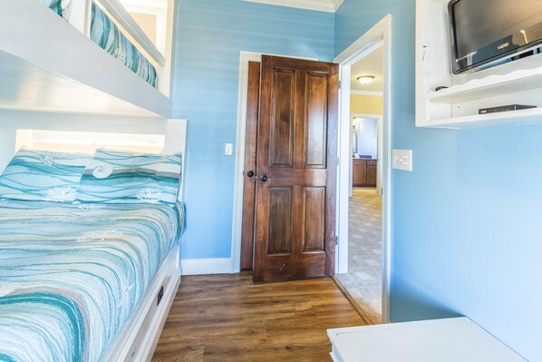 Une chambre à coucher avec un lit, une porte en bois et un téléviseur fixé au mur.