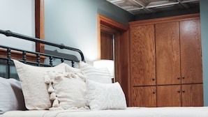 A bedroom with a bed, wooden wardrobe, and a ceiling with a geometric pattern.