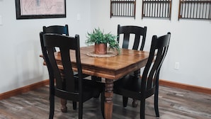 A dining table with four chairs, a potted plant, and a framed map on the wall.