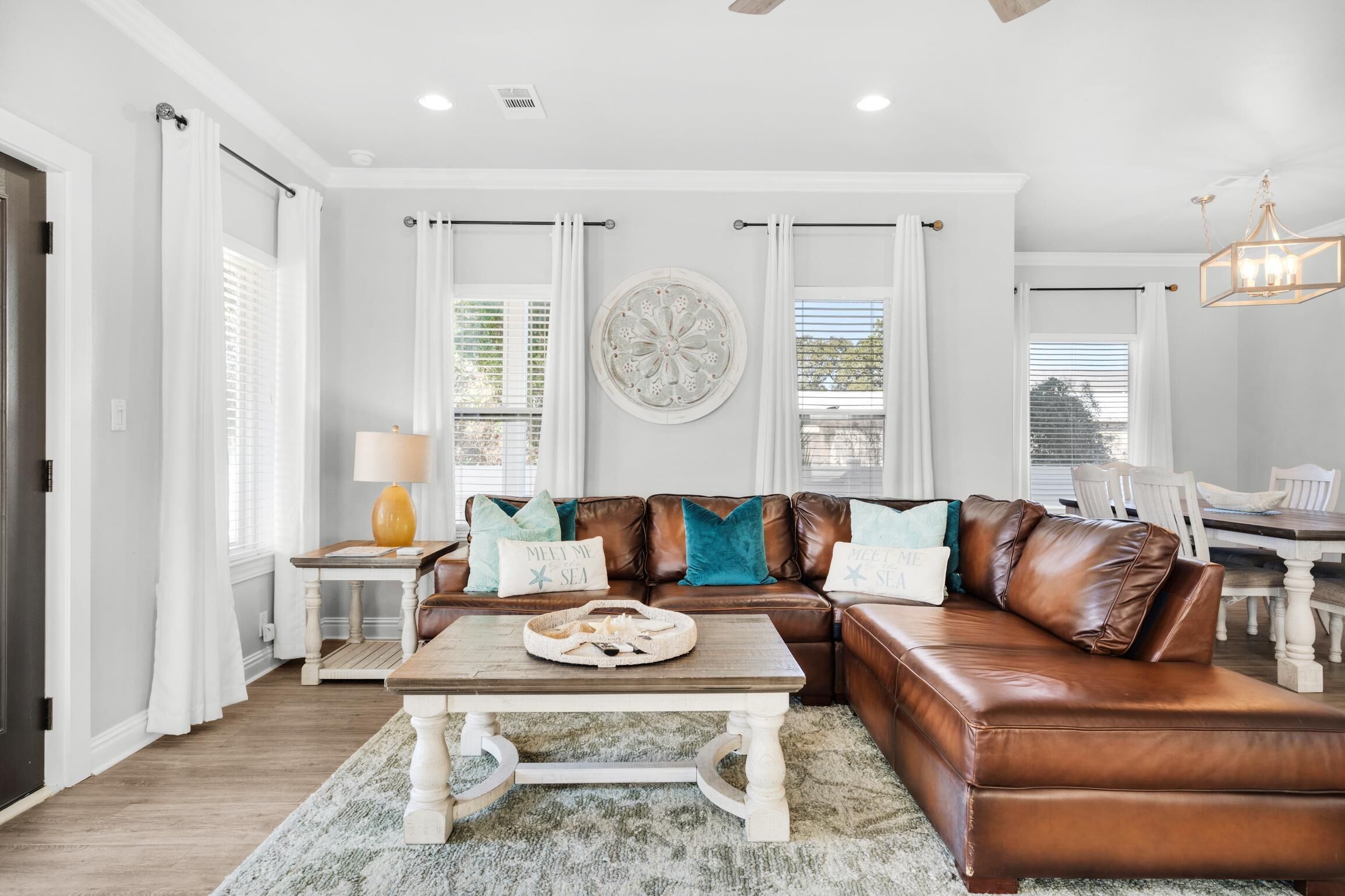 A living room with a brown leather sectional sofa, a wooden coffee table, and a round decorative wall piece.