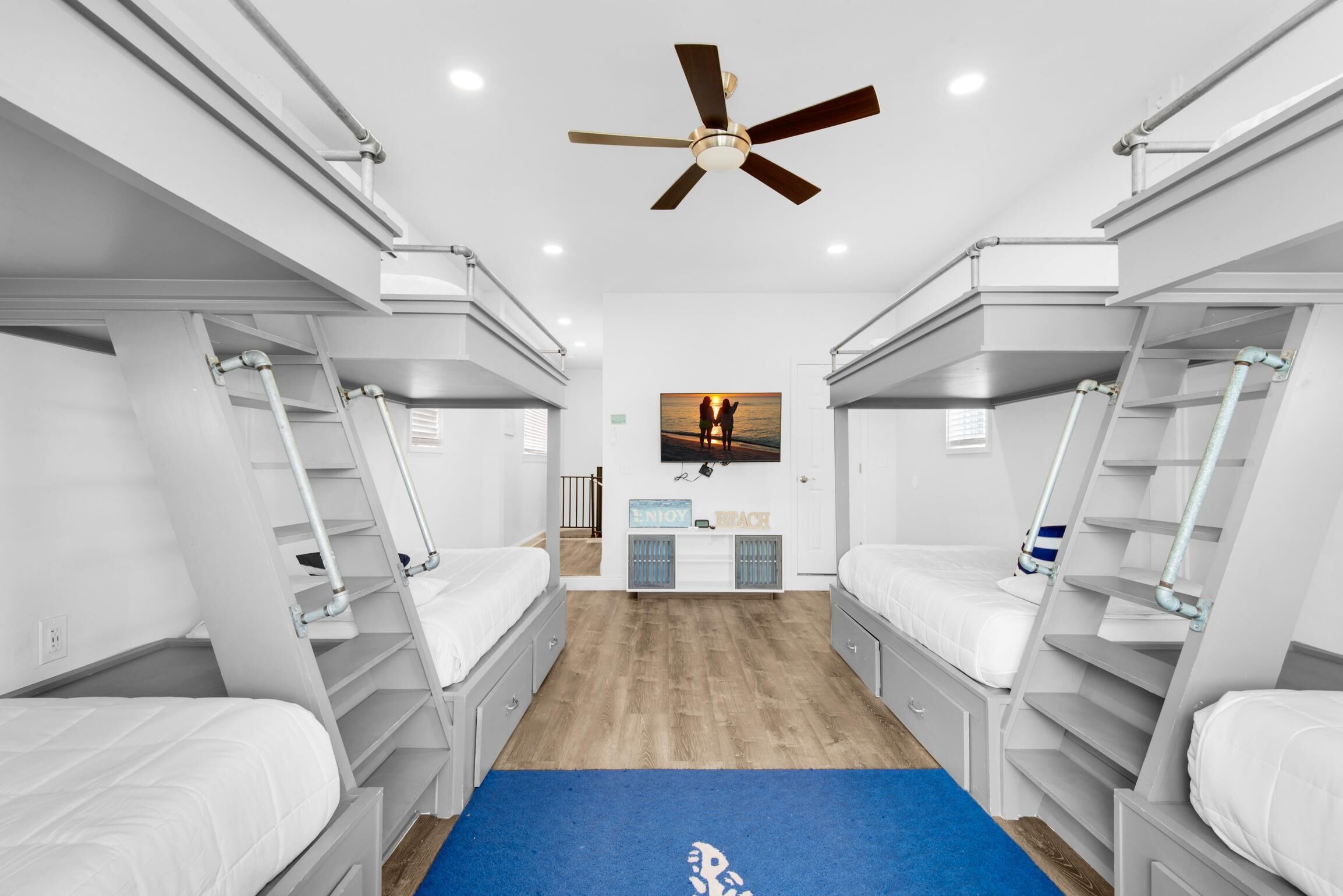 A room with bunk beds, a ceiling fan, and a wall-mounted picture.