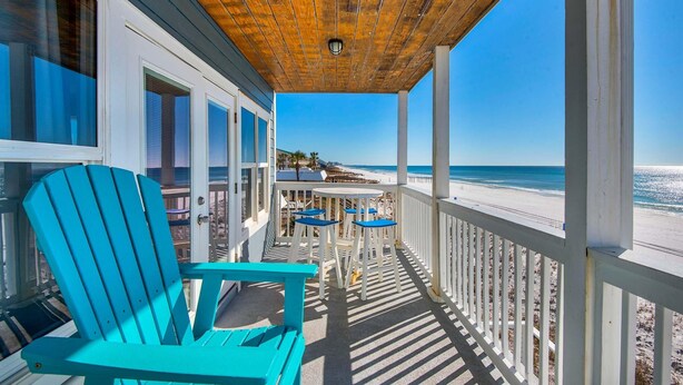A covered porch with a wooden ceiling, white railings, and a view of the beach. - Pointe of View (Destin)