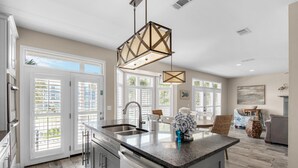 A modern kitchen with a central island, stainless steel appliances, and a large window providing natural light.