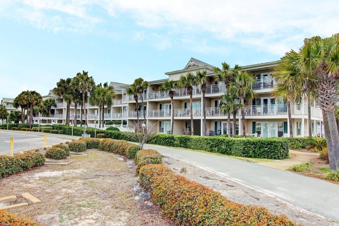 A multi-story hotel with balconies, palm trees, and a parking lot.