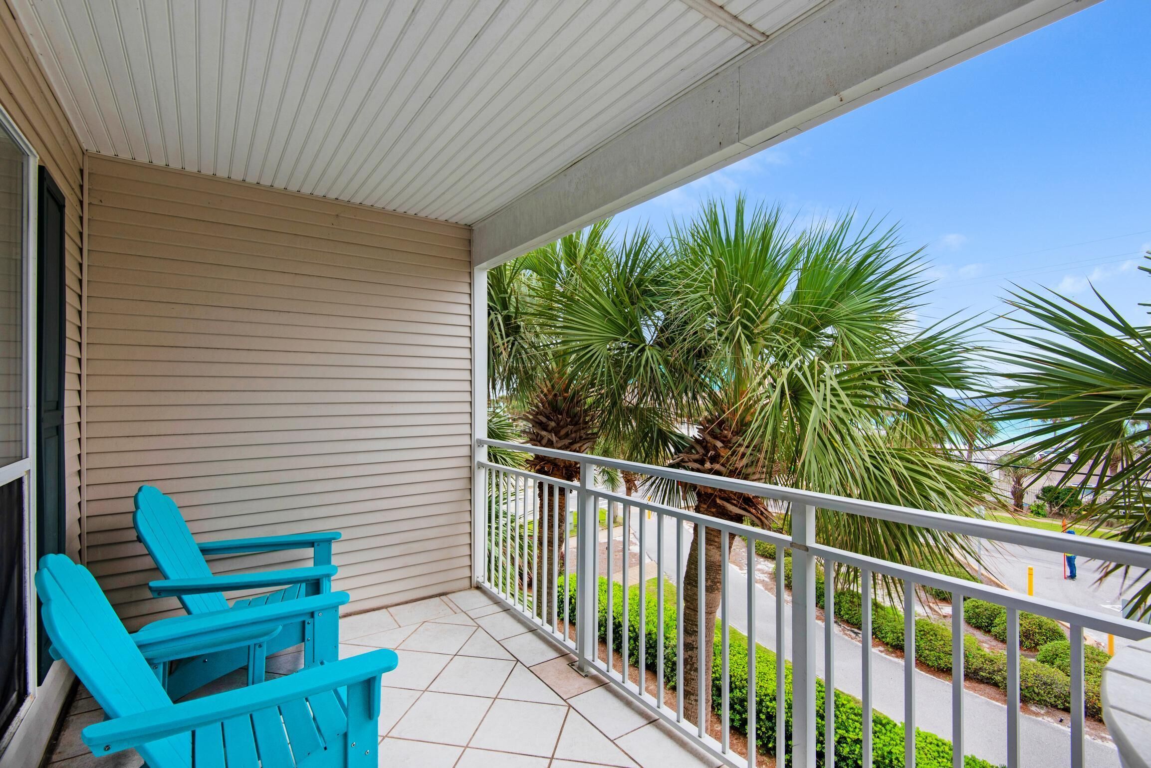 A balcony with a view of palm trees and a road.