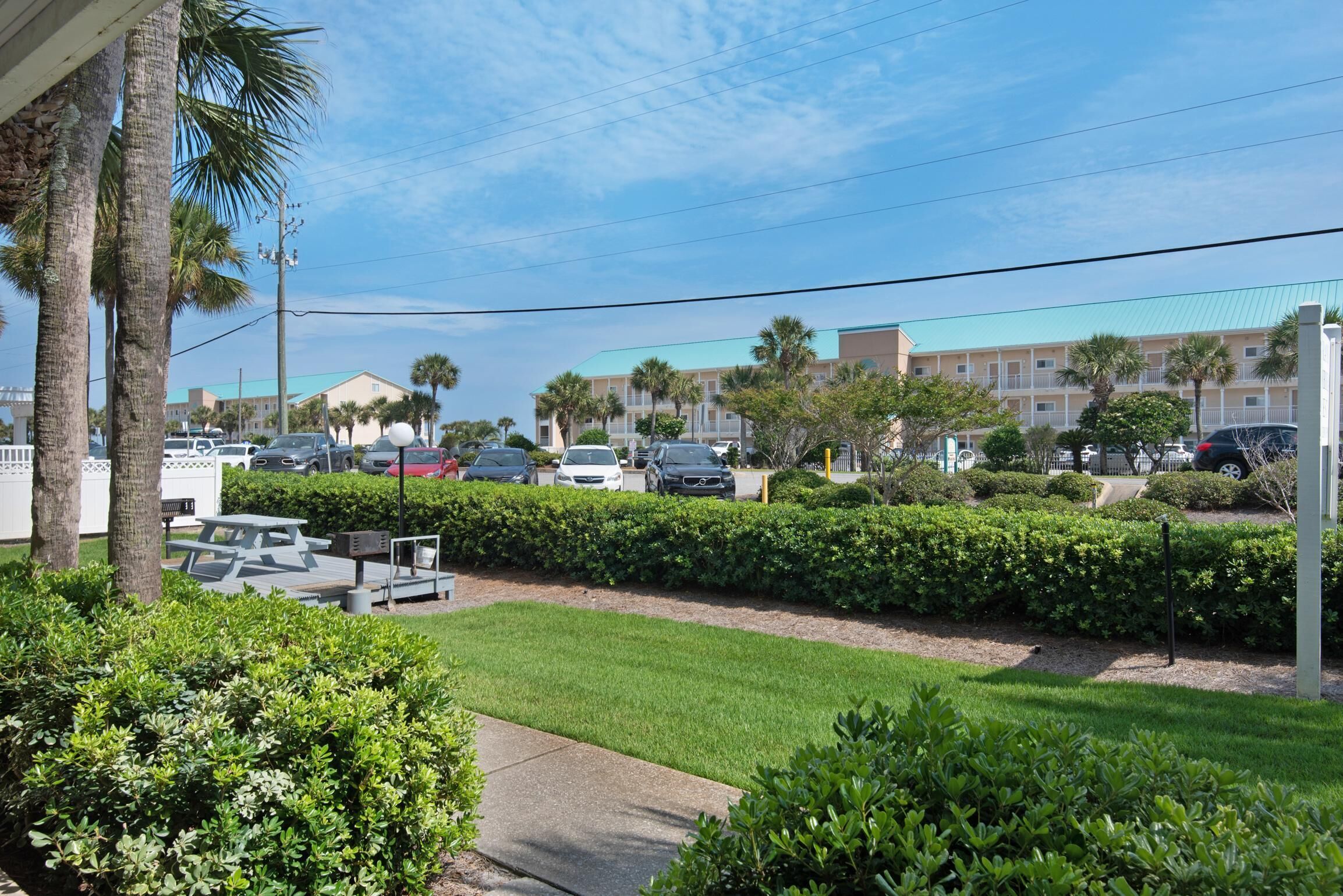 A parking lot with several cars, a picnic table, and a well-maintained lawn with hedges.