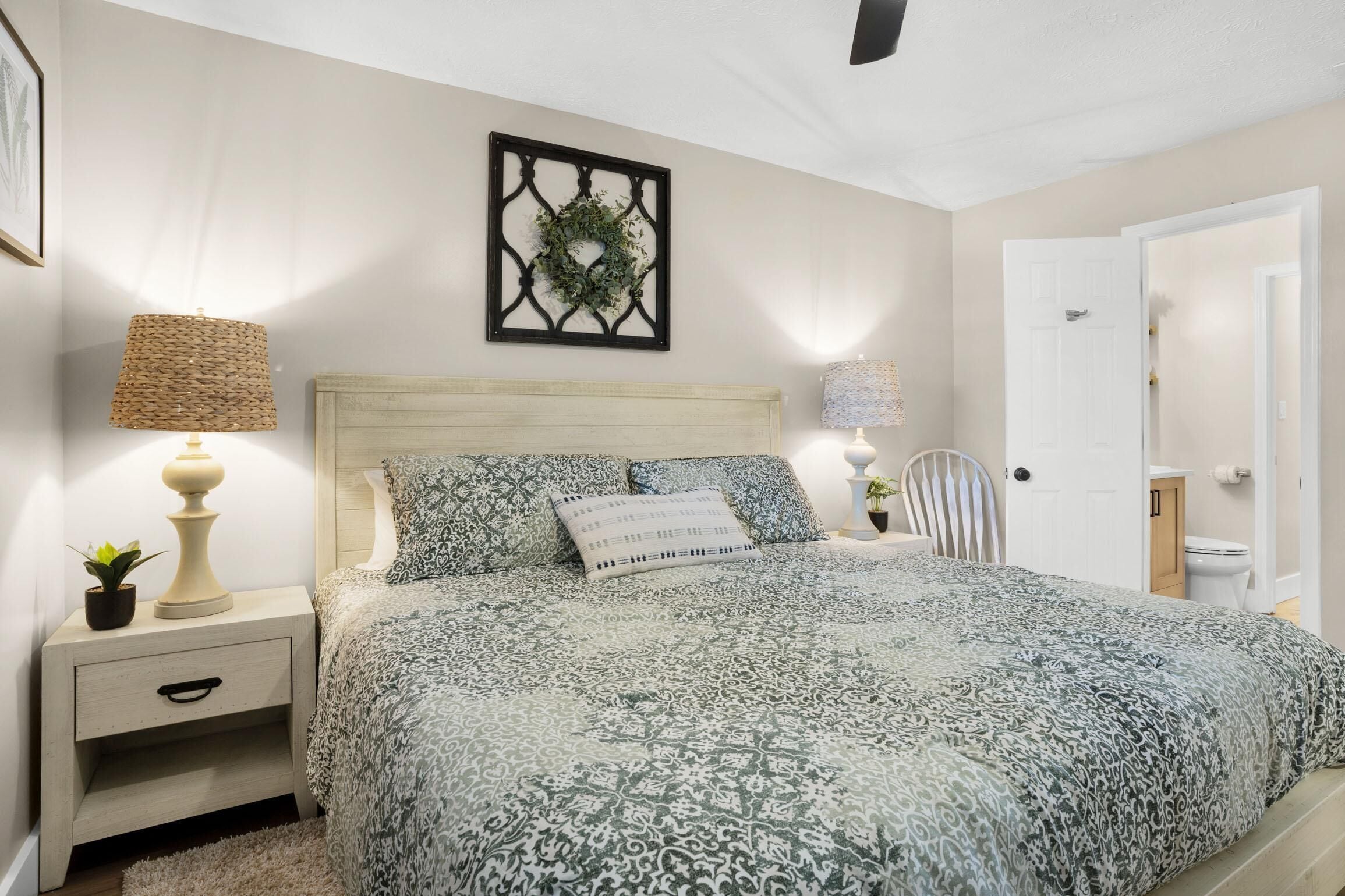 A bedroom with a bed, nightstands, a wall-mounted decorative item, and a door.