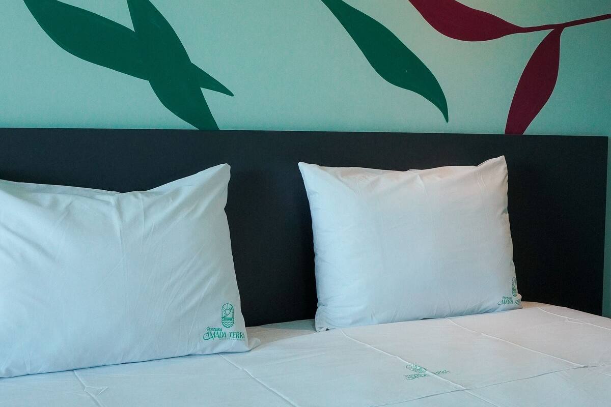 Una habitación de hotel con una cama, ropa de cama blanca y una pared con diseño de hojas.