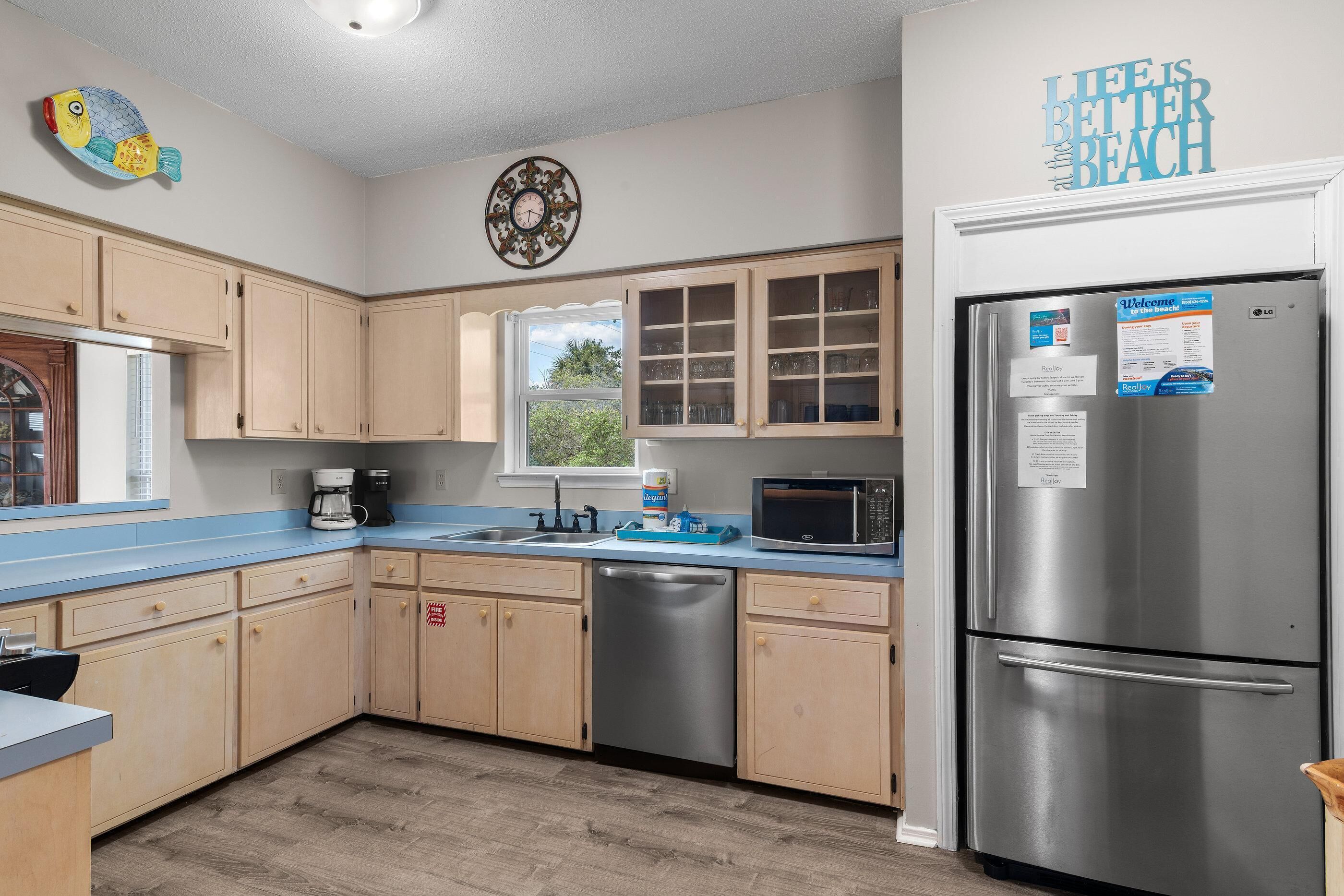 A kitchen with wooden cabinets, a stainless steel refrigerator, a microwave, and a coffee maker.