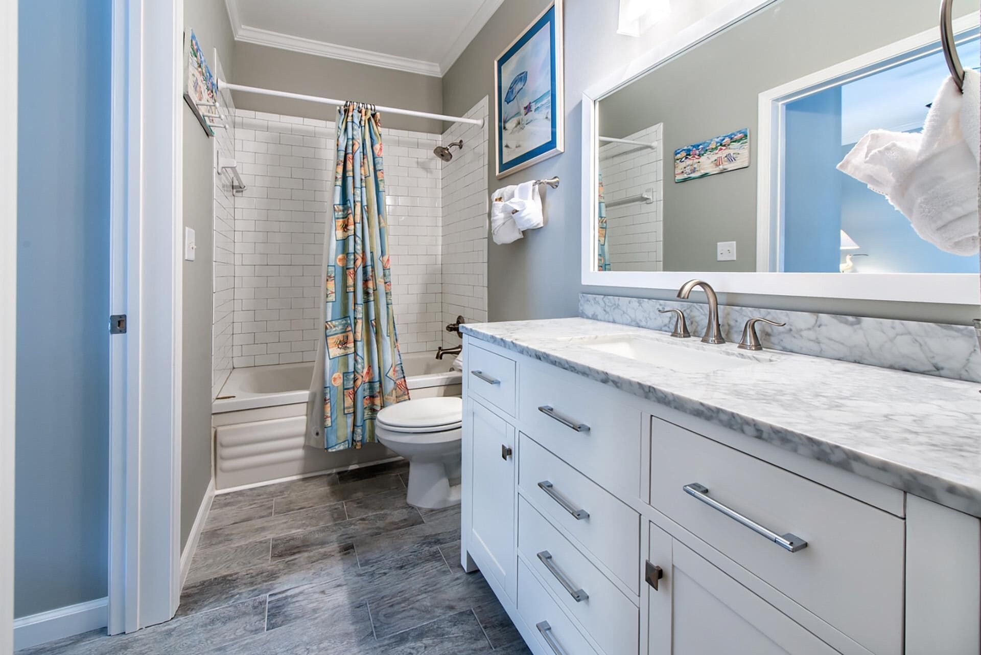A modern bathroom with a shower, toilet, and vanity with a large mirror.