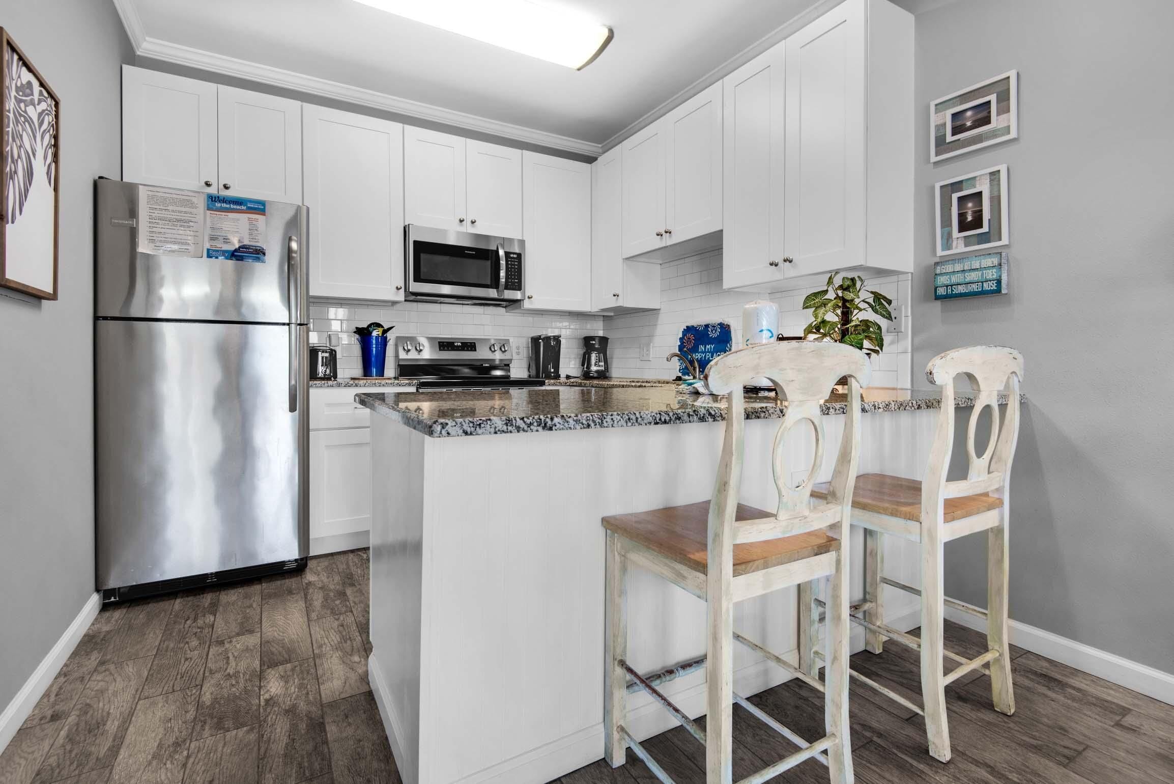 A kitchen with white cabinets, stainless steel appliances, and a granite countertop.
