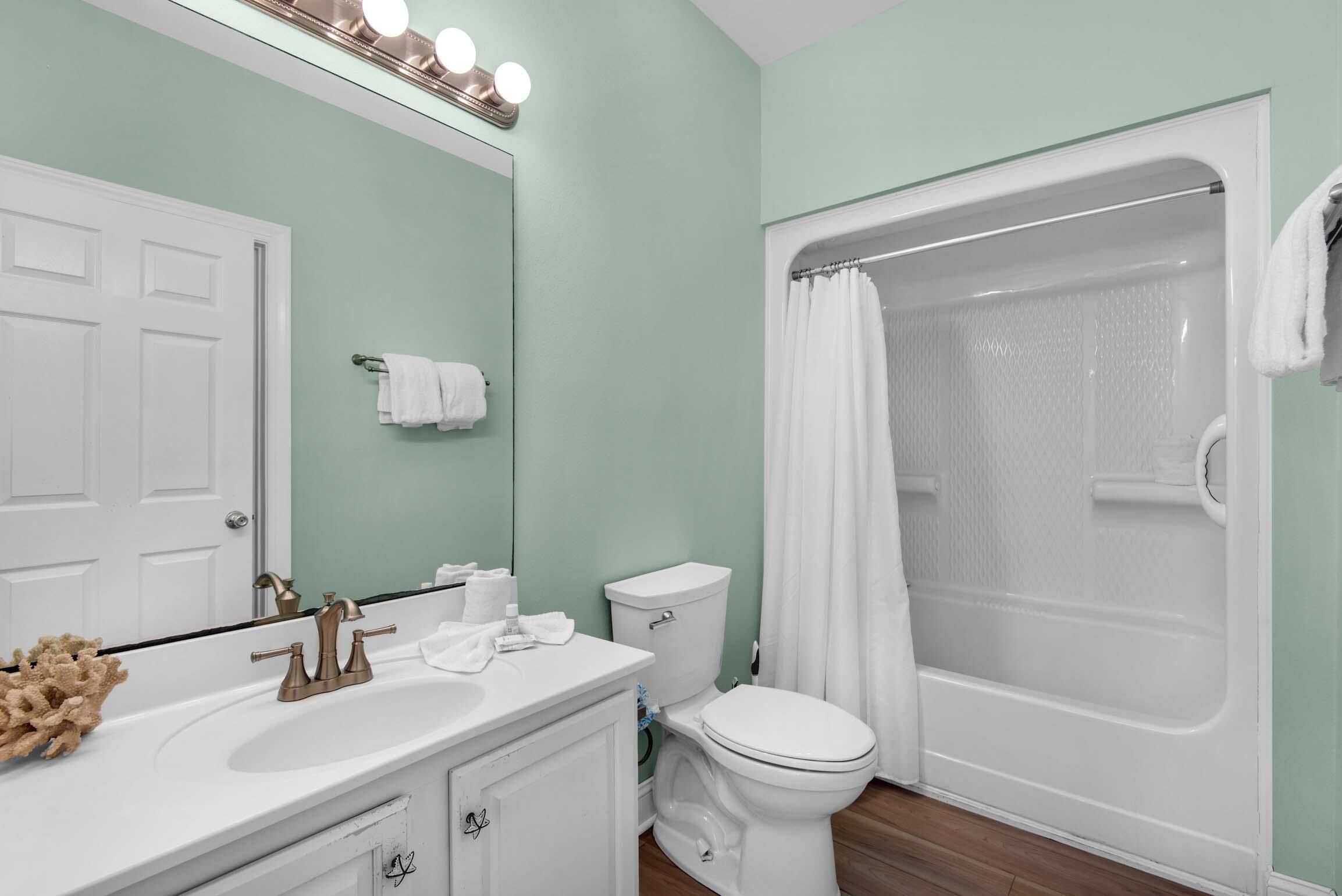 A bathroom with a white sink, vanity, toilet, and a glass-enclosed shower.