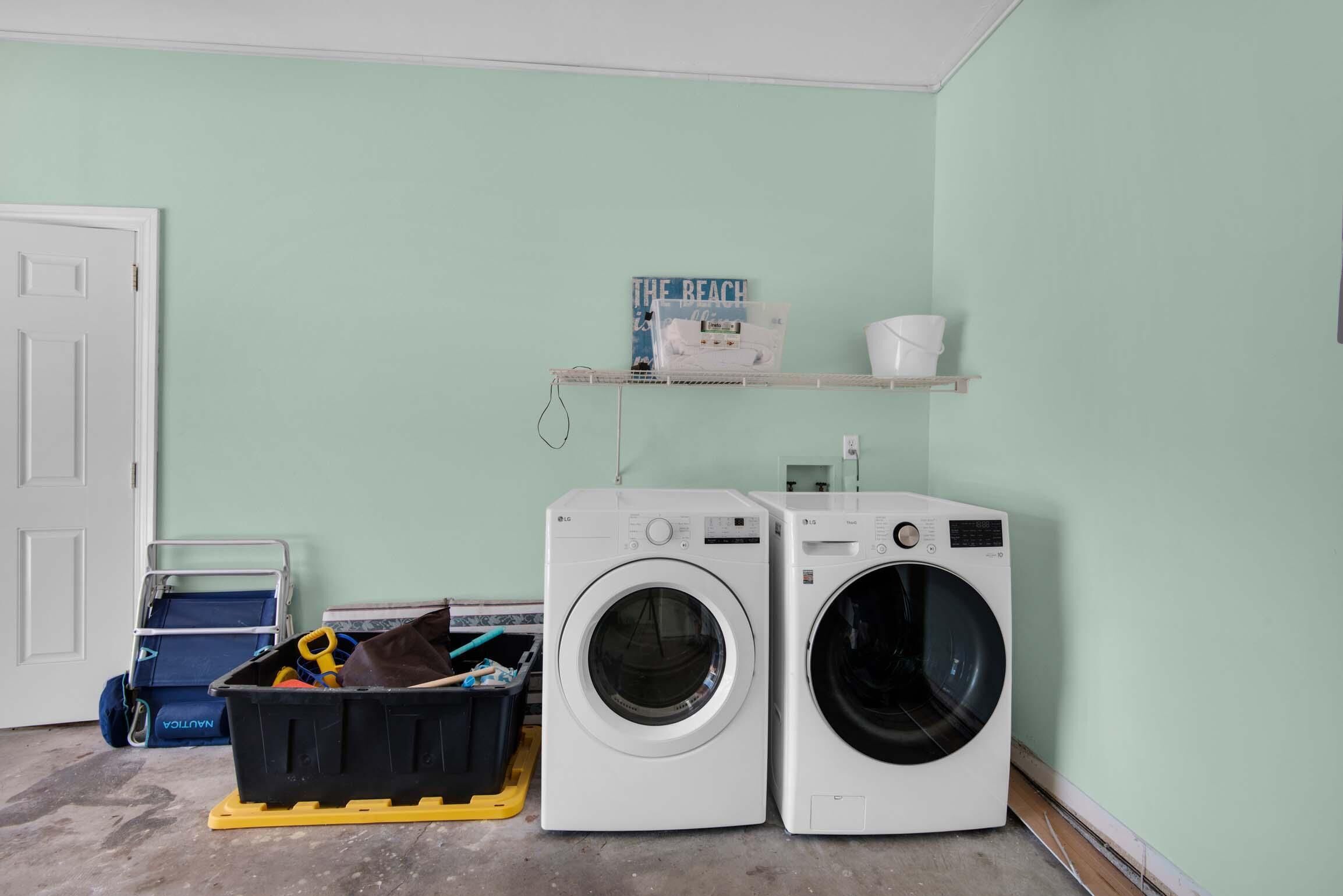A laundry room with two LG washing machines, a shelf with a book and a bucket, and a storage bin with cleaning supplies.