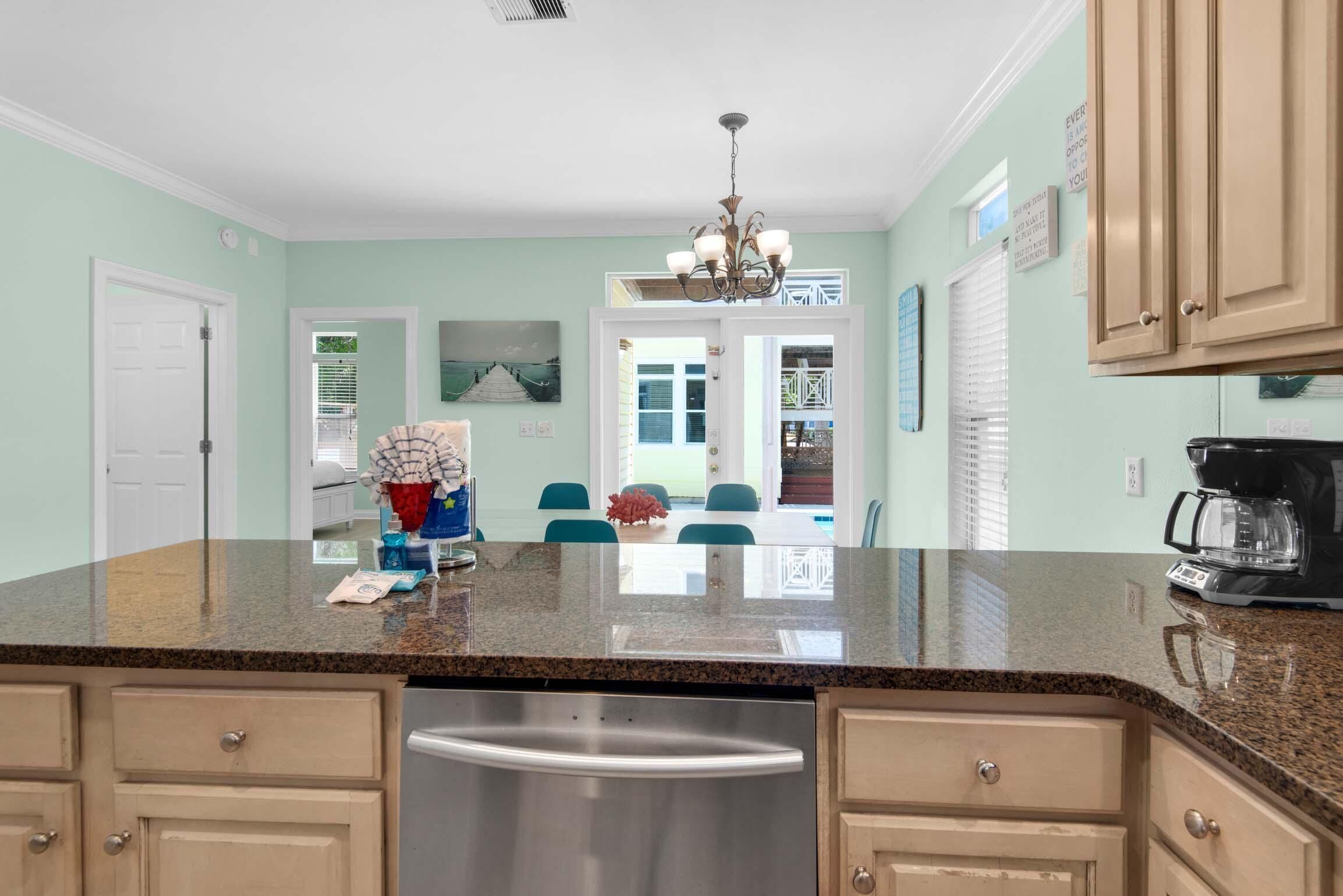 A kitchen with granite countertops, stainless steel appliances, and light green walls.