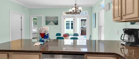 A kitchen with granite countertops, stainless steel appliances, and light green walls.
