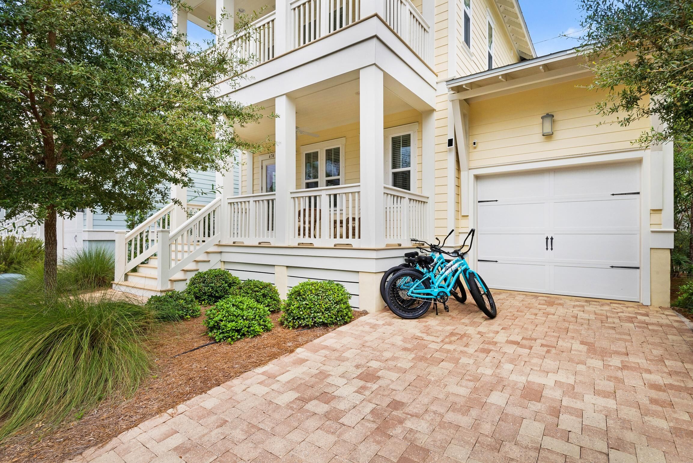A two-story house with a front porch, a garage, and a bicycle parked in the driveway.