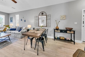 A dining area with a wooden table, chairs, and a console table with decorative items. - Topsail Village 721- Shore Bird Sanctuary (Santa Rosa Beach)