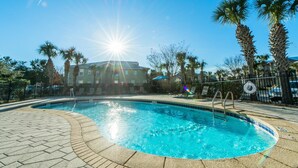 A swimming pool with a tiled edge, surrounded by palm trees and a building in the background. - Topsail Village 422 (Santa Rosa Beach)