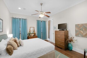 A bedroom with a bed, a dresser, a television, and a ceiling fan. - The Light House (Santa Rosa Beach)