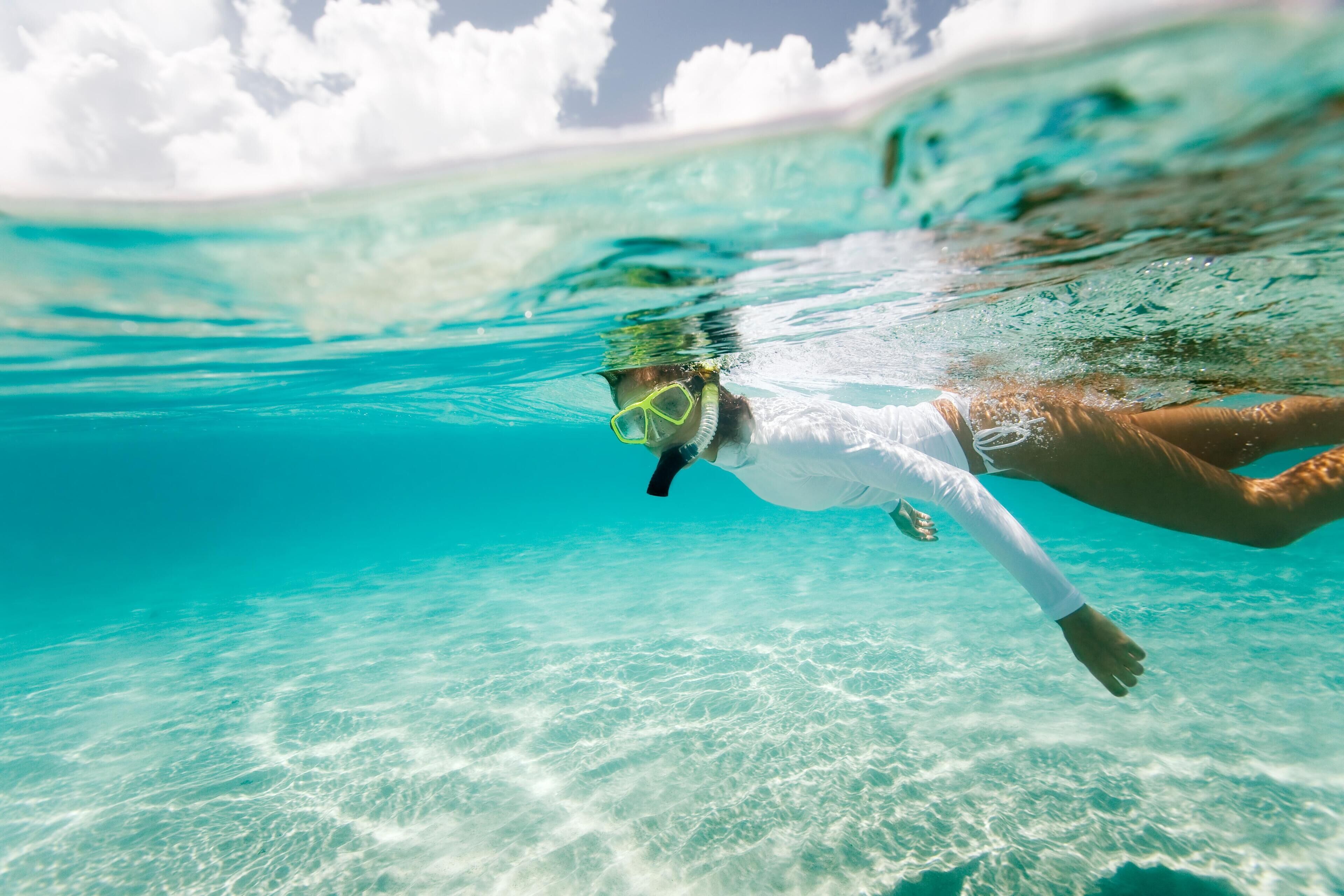 A person swimming underwater in clear turquoise water.