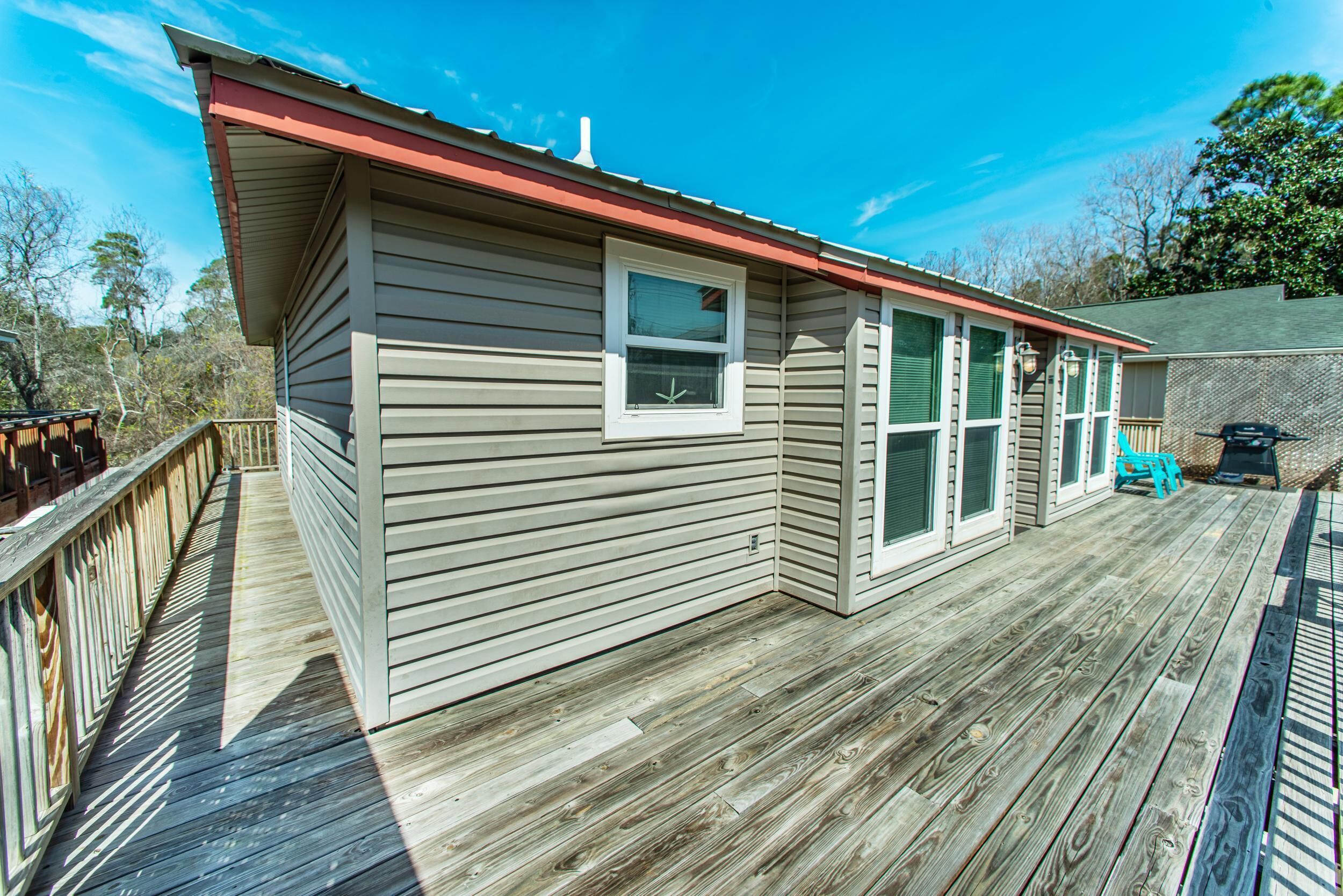 A single-story building with a wooden deck, a red roof, and a window.